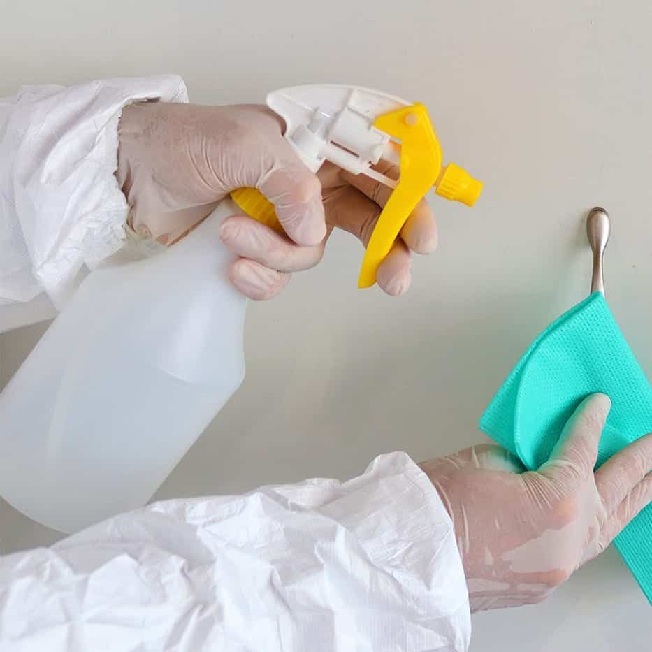 Gloved hands with a spray bottle and cloth