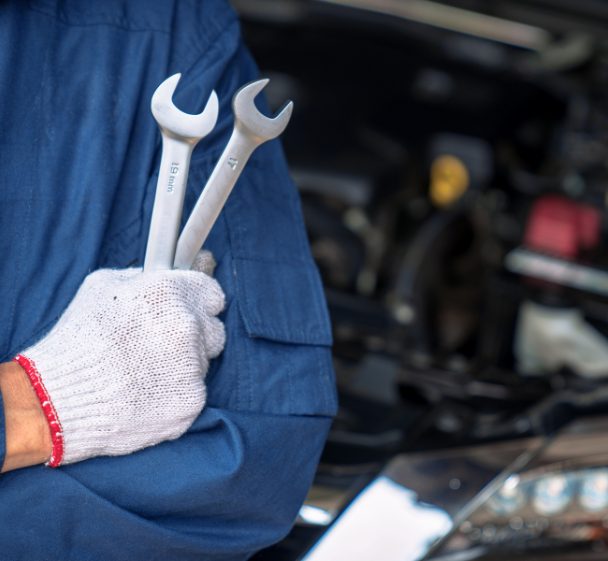 Gloved hand holding two spanners